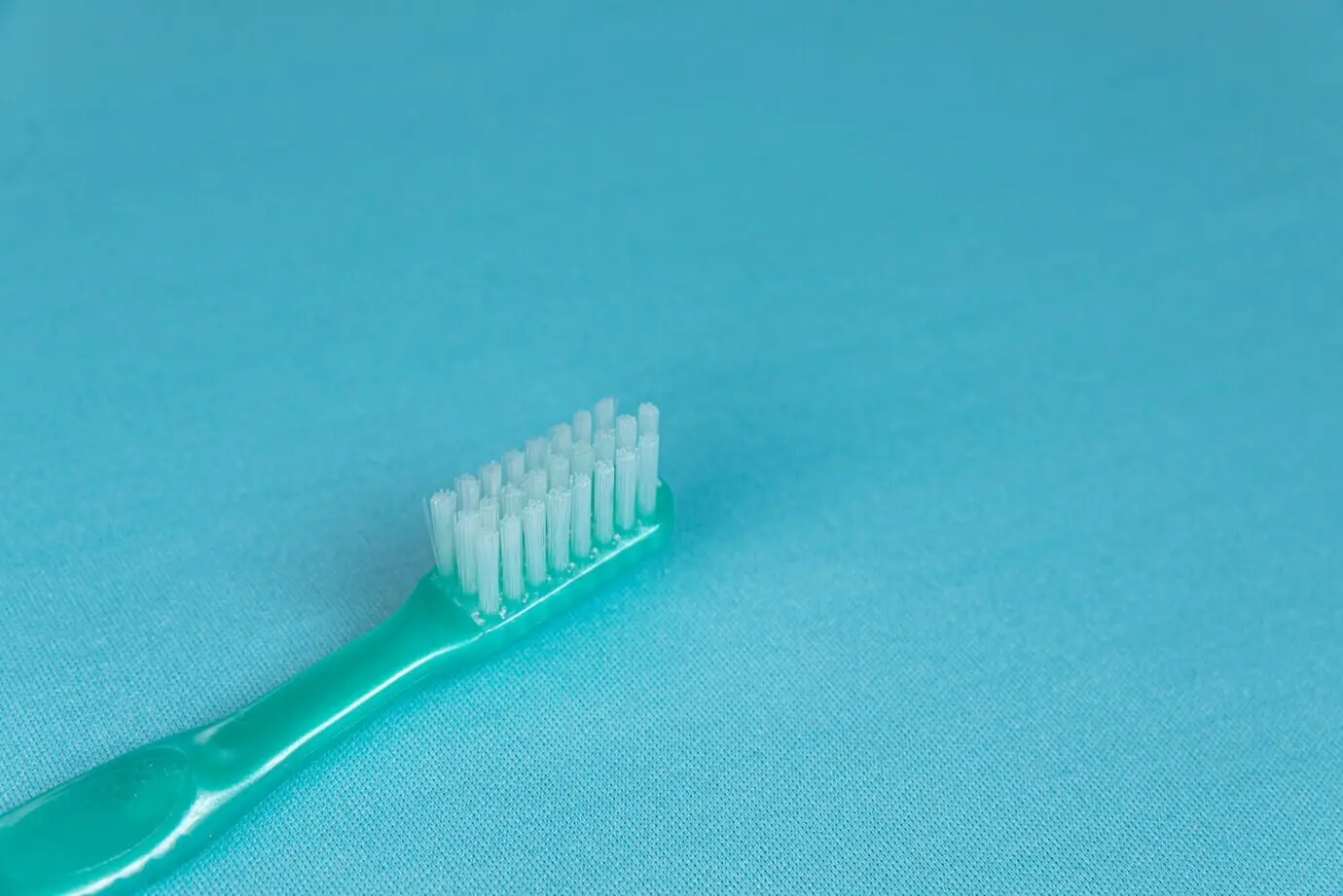 Бирюзовая зубная щётка на синей поверхности